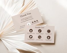 two business cards sitting next to each other on top of a white surface with brown accents