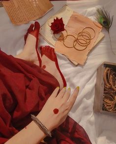 a woman laying on top of a bed next to an open book and ring box