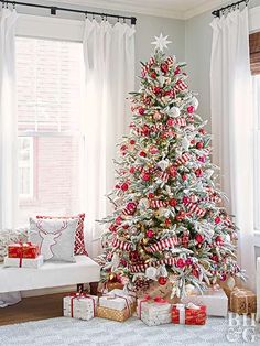 a white christmas tree with red and silver ornaments in a living room decorated for the holidays