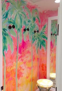 a bathroom with palm trees painted on the wall and two stools in front of it