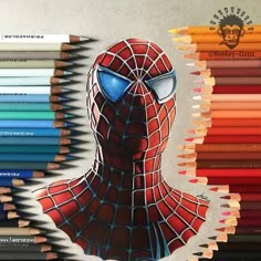 a drawing of a spider man with colored pencils in front of it and the image of his face