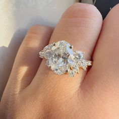 a woman's hand holding an engagement ring with three pear shaped diamonds on it