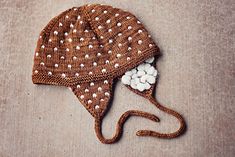 a brown hat with white dots on it sitting on top of a wooden table next to a pair of scissors