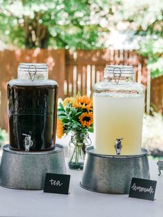 there are two jars with drinks on top of them and some flowers in the vase