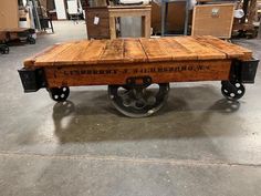 an old wooden table with wheels in a warehouse