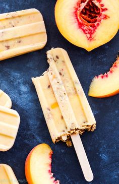 an ice cream popsicle with slices of peaches and chocolate chip toppings on a blue surface