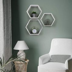 three hexagonal shelves on the wall above a white chair and lamp in a living room