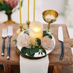 a white plate topped with flowers next to a candle on top of a wooden table