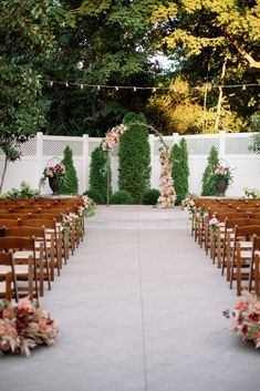 an outdoor ceremony setup with wooden chairs and flowers