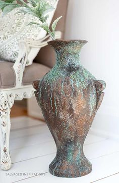 a vase sitting on the floor next to a chair with a potted plant in it