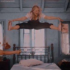 a woman jumping in the air over a bed next to another person on a bed