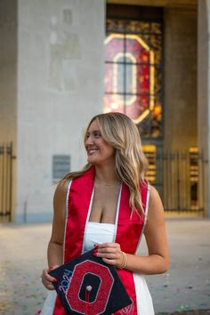 a woman in a red and white dress holding a black bag with the letter o on it