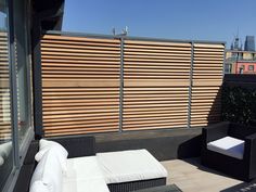 an outdoor patio with wicker furniture and wooden slatted privacy screens on the roof