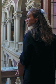 a woman standing in front of a window with a bow on her head