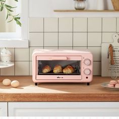 a pink toaster oven sitting on top of a counter next to eggs and bread