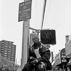 a man sitting on top of a pole next to a street sign