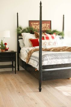 a bed sitting on top of a wooden floor next to a night stand with christmas decorations