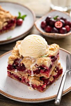 a piece of pie on a plate with ice cream and cherries in the background