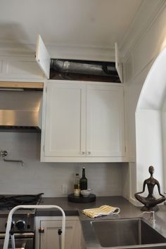 a kitchen with white cabinets and stainless steel sink