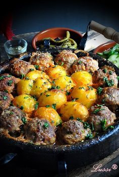 a pan filled with meatballs and vegetables on top of a table