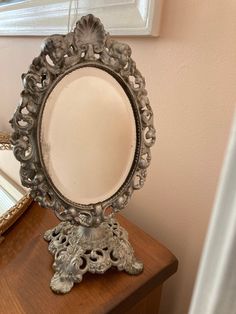 a mirror sitting on top of a wooden table next to a mirror with an ornate frame