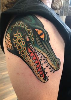 a woman's arm with a tattoo design on it, showing the head of an alligator