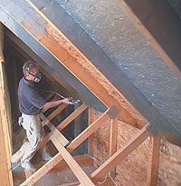 a man standing on top of a wooden floor next to a ladder and holding a hammer