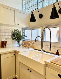 a kitchen with white cabinets and black lights hanging from the ceiling over the sink area