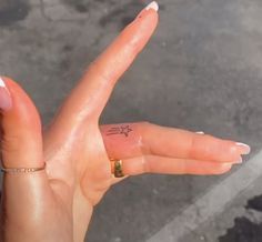 a person's hand with a tiny star tattoo on their left thumb and fingers