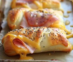 ham and cheese wrapped in bread on a baking sheet with mustard drizzled over it