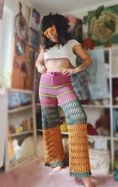 a woman wearing crocheted pants and a crop top posing with her hands on her hips