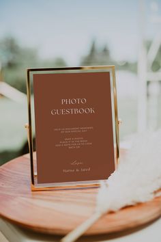 a photo guest book sitting on top of a wooden table next to a white feather