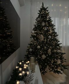 a decorated christmas tree in a living room with white lights and ornaments on the floor