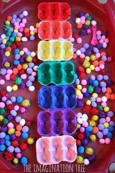 an art project made with colored plastic cups and pom poms on a tray