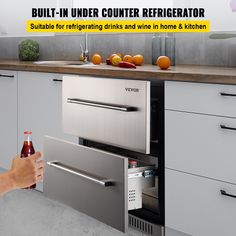 a person opening the door to an appliance in a kitchen that has stainless steel cabinets and drawers