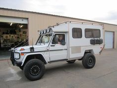 a white truck parked in front of a building with a man sitting in the driver's seat