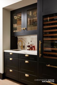 a kitchen with black cabinets and gold handles