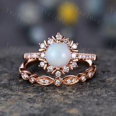 a white opal and diamond ring sitting on top of a rock