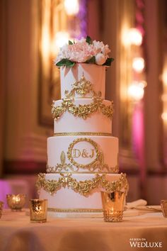 a three tiered wedding cake sitting on top of a table next to gold cups