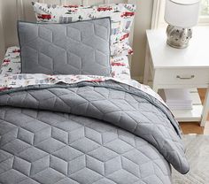 a bed in a bedroom with a gray comforter and matching pillow cases on it