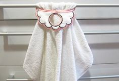 a white towel hanging on the side of a wall with an embroidered flower in it