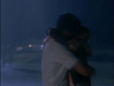 two people hugging in the rain at night