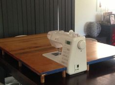 a sewing machine sitting on top of a wooden table in front of a black wall