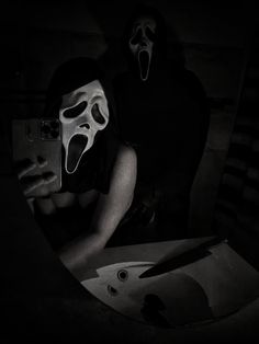 two people with masks on their faces are looking at a cell phone in the dark