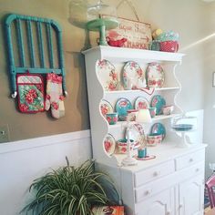 a white china cabinet sitting next to a potted plant