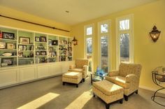 a living room with two chairs and a coffee table in front of a bookcase