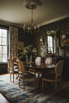 a dining room table with chairs and a rug in front of the window that has curtains on it