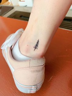 a small pine tree tattoo on the ankle