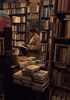 a woman standing in front of a bookshelf filled with lots of book's