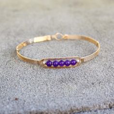 A sweet little bracelet of five strands of 14kt gold filled wire with a center design featuring five 4mm genuine amethyst beads and accented with two smaller beads. Perfect for that February birthday girl! Stackable, too, along with many of my other wirewrapped bracelets! The sturdy built-in hook and eye clasp is easy to get on and off by yourself. Choose the size you need for a comfortable custom fit. Also available in sterling silver. Hand-strung Friendship Bracelet Jewelry, Hand-strung Friendship Bracelet, Hand Wrapped Bangle Jewelry For Gifts, Nickel-free Gold Bracelet For Friendship, Gold Nickel-free Bracelets For Friendship, Gold Nickel-free Bracelet For Friendship, Adjustable Spiritual 14k Gold Filled Beaded Bracelet, Spiritual Adjustable 14k Gold Filled Beaded Bracelet, Elegant Friendship Wrap Bracelet